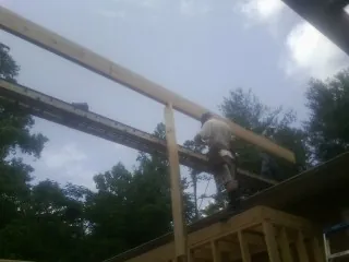 Carpenter setting a ridge beam over a new addition frame — Ice Dam Removal by Roofing Brothers in Greenville