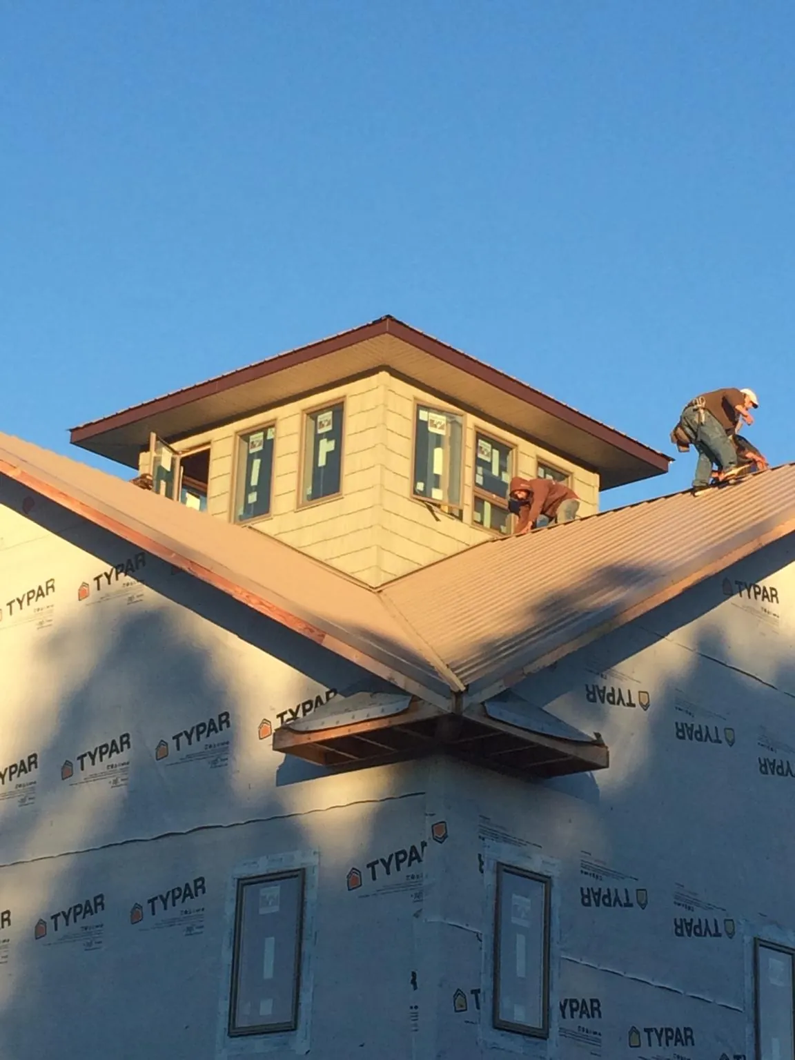 Roofers working around a rooftop cupola on a new metal roof at sunset — Roof Waterproofing in Greenville by Roofing Brothers